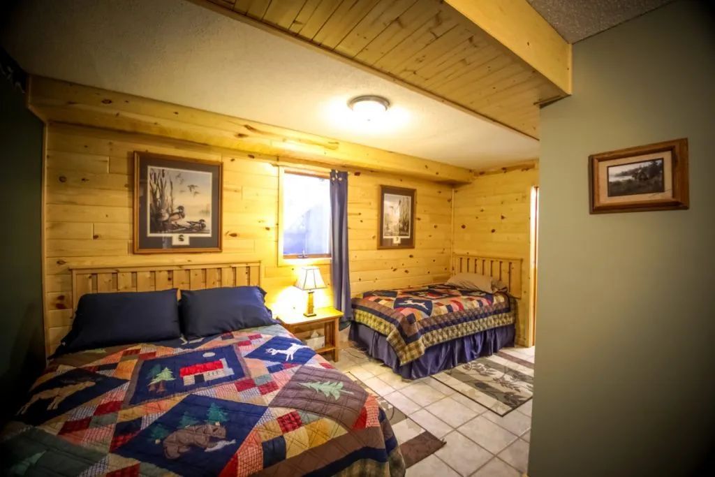 A bedroom with two beds and two pictures on the wall.