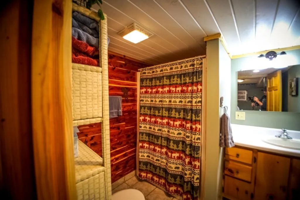 A bathroom in a log cabin with a shower curtain and a sink.