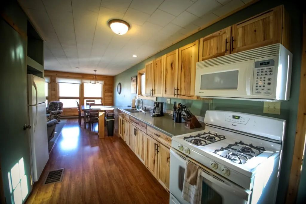 A kitchen with a stove , microwave , refrigerator and wooden cabinets.