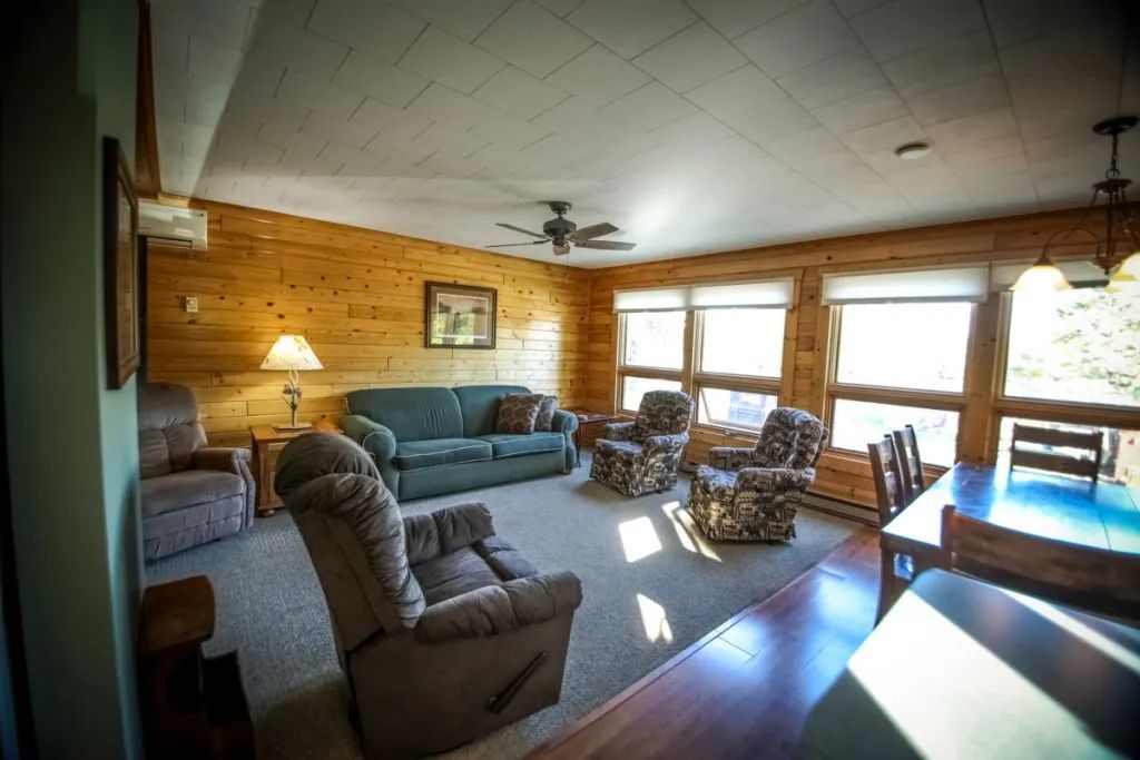 A living room with a couch , chairs , a table and a ceiling fan.