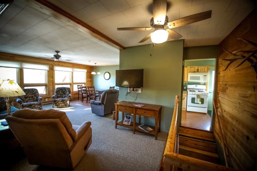 A living room with a ceiling fan and a flat screen tv