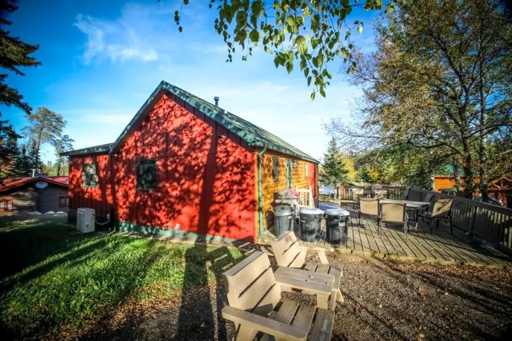 A red house with a wooden deck and benches in front of it.