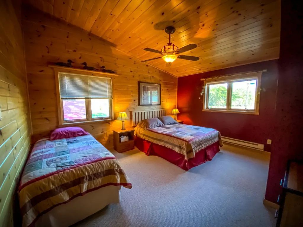 A bedroom with two beds and a ceiling fan.