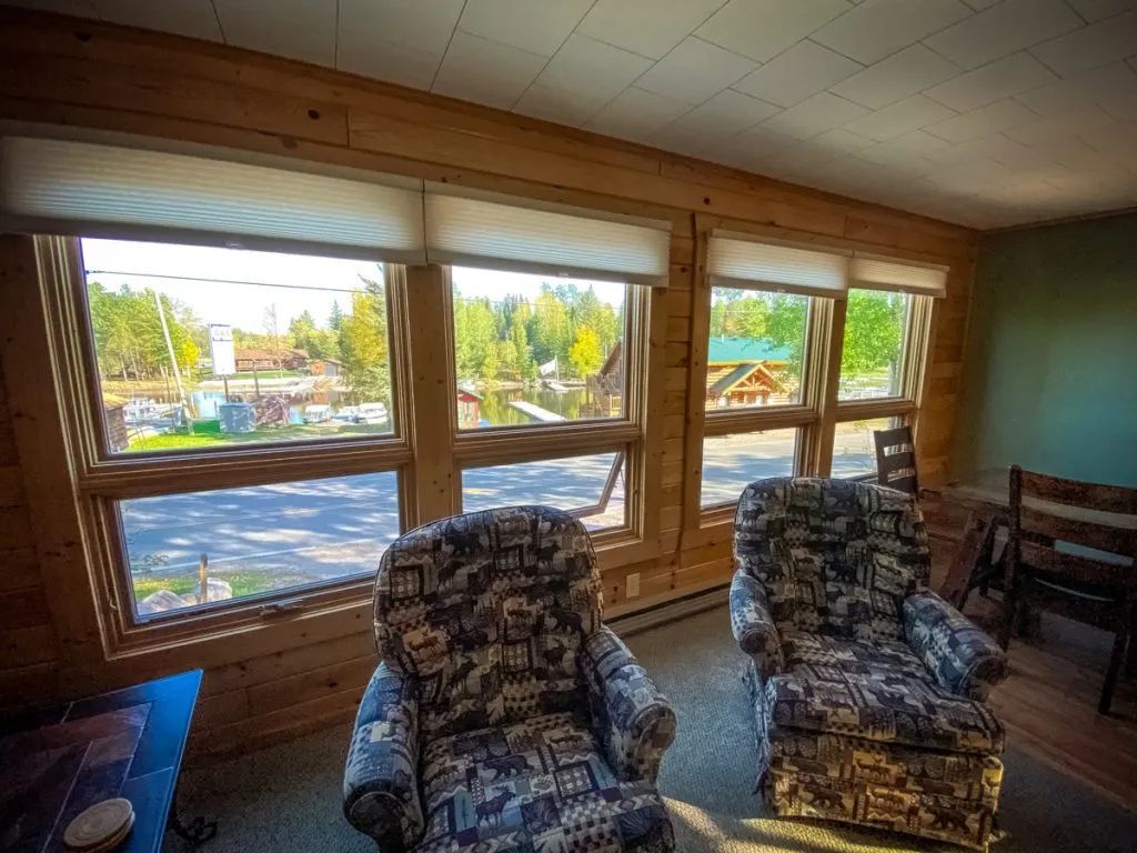A living room with two chairs and a lot of windows.