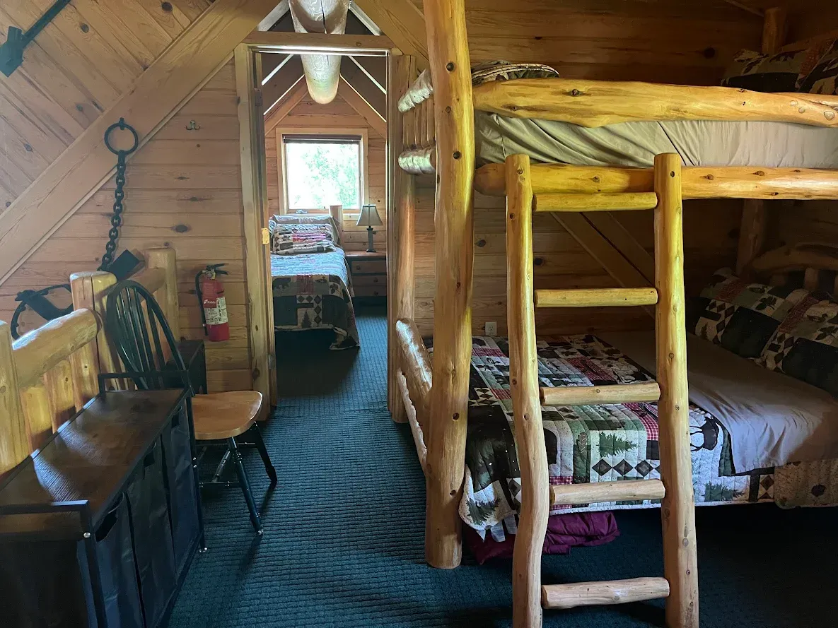 A bathroom in a log cabin with a toilet , sink and mirror.