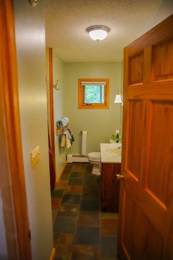 A bathroom with a toilet , sink , and window.