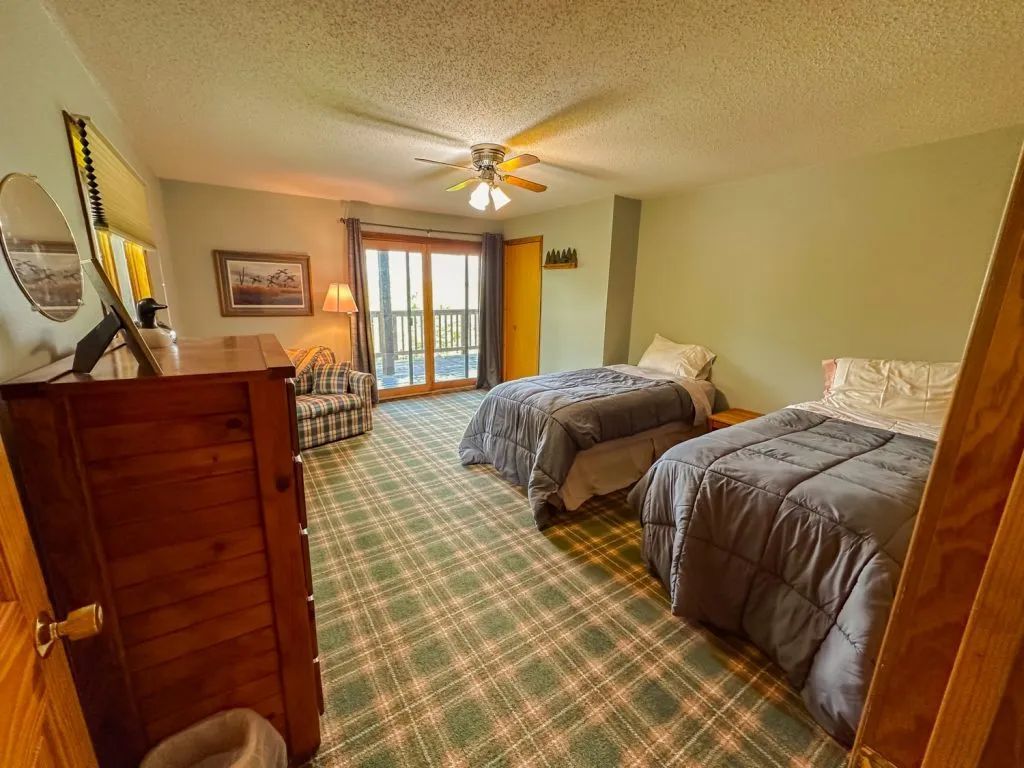 A bedroom with two beds , a dresser , a chair and a ceiling fan.
