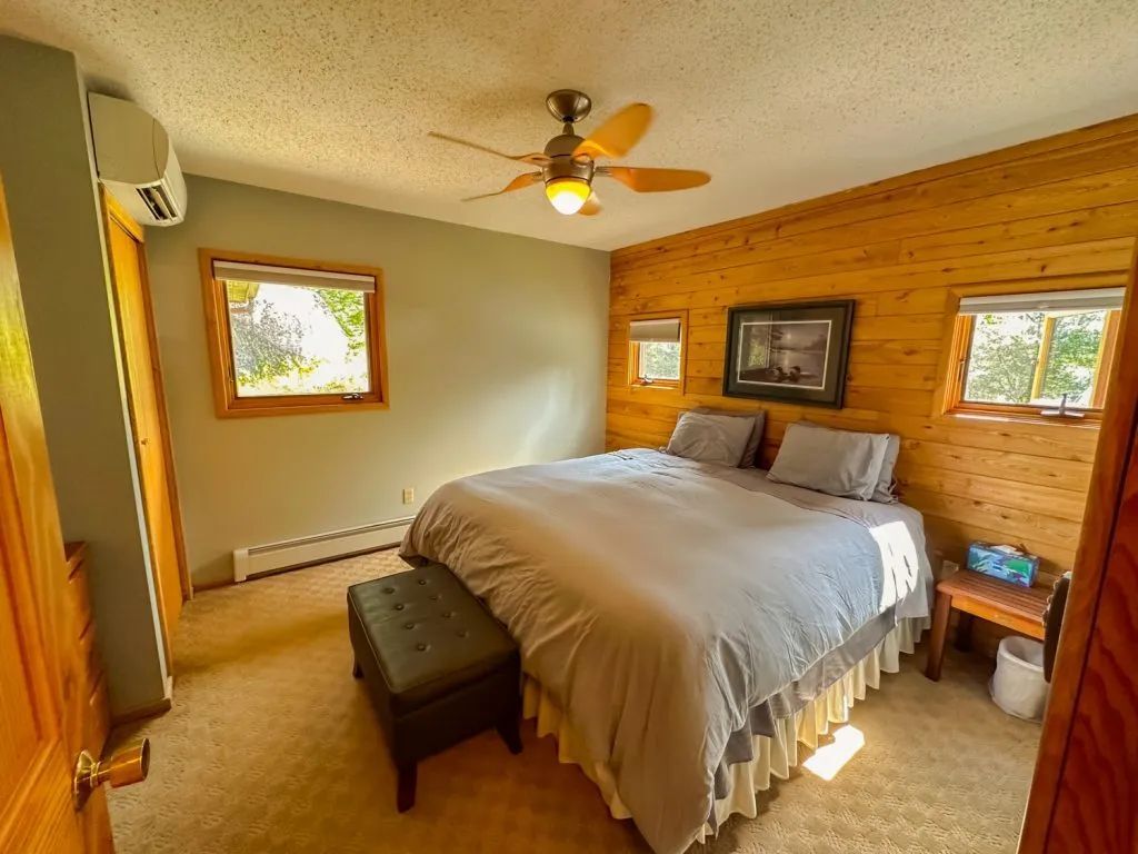 A bedroom with a king size bed and a ceiling fan.