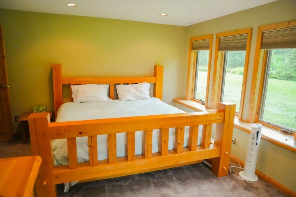 A bedroom with a large wooden bed and a fan.
