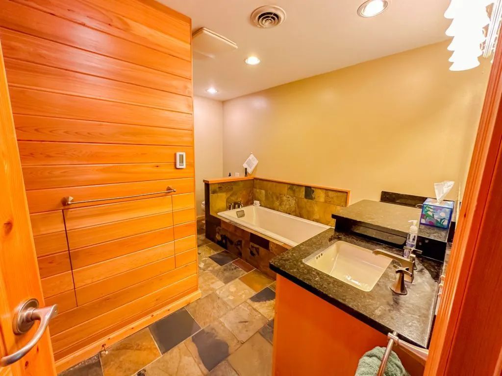 A bathroom with a tub , sink and mirror.