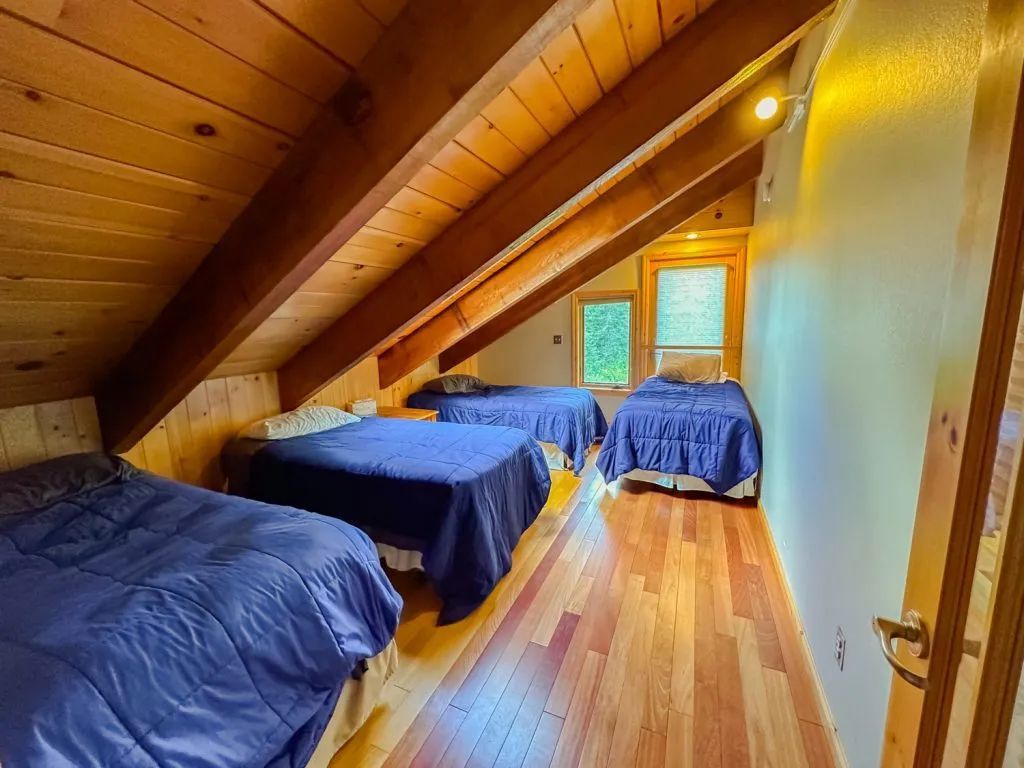 There are three beds in the attic of a house.