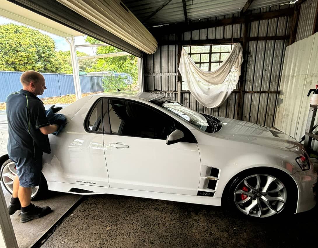A Man Is Standing Next To A White Car In A Garage — SnP Mechanical & Detailing In Murwillumbah, NSW