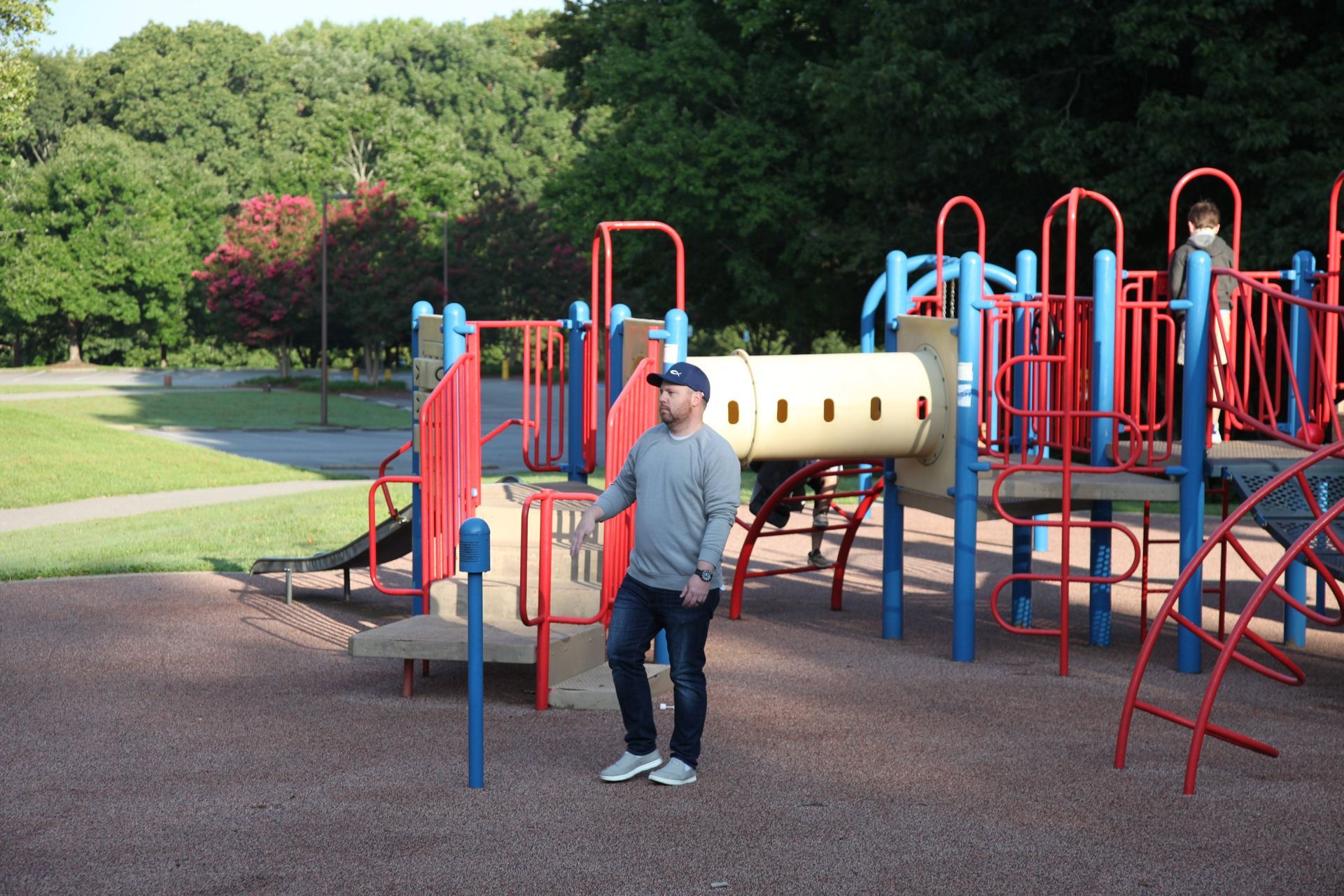 A man standing in front of a playground in a park