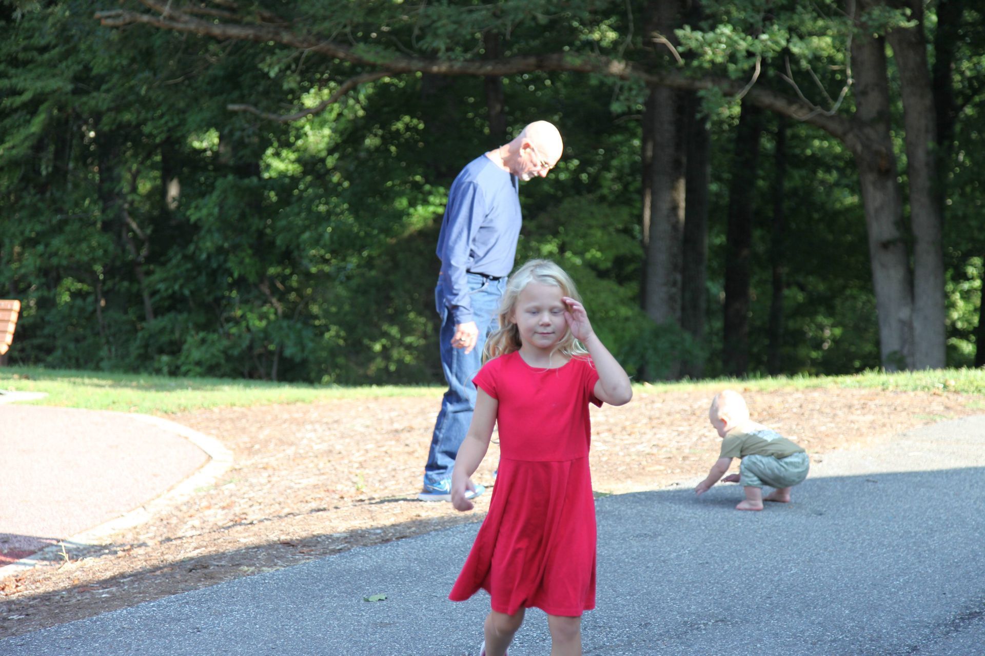 A little girl in a red dress is walking down the street