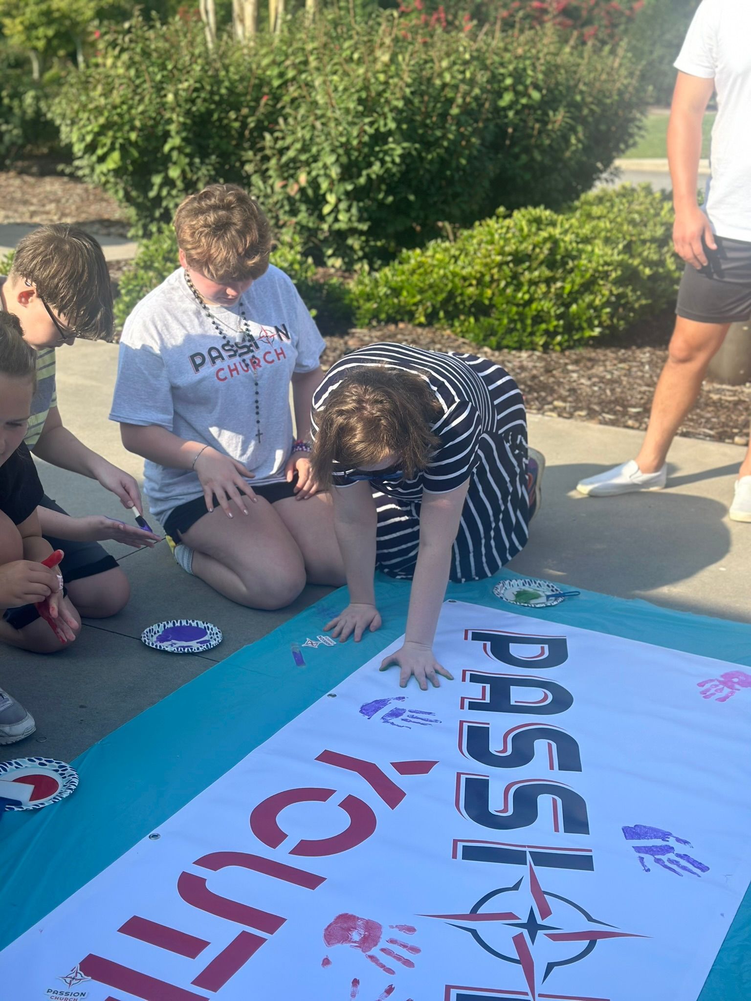 A group of people are painting a large sign on the ground.