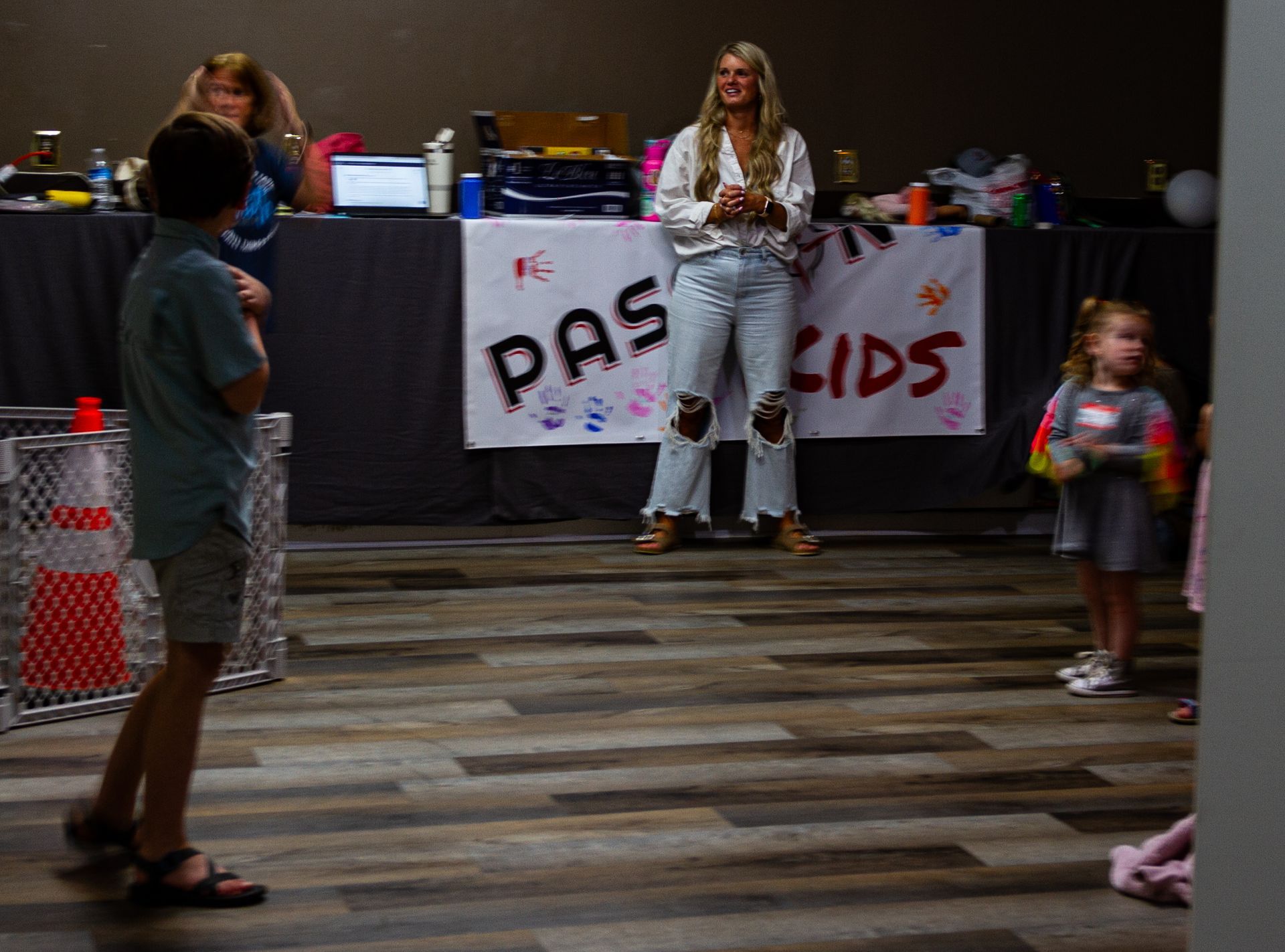 A woman stands in front of a sign that says pas kids