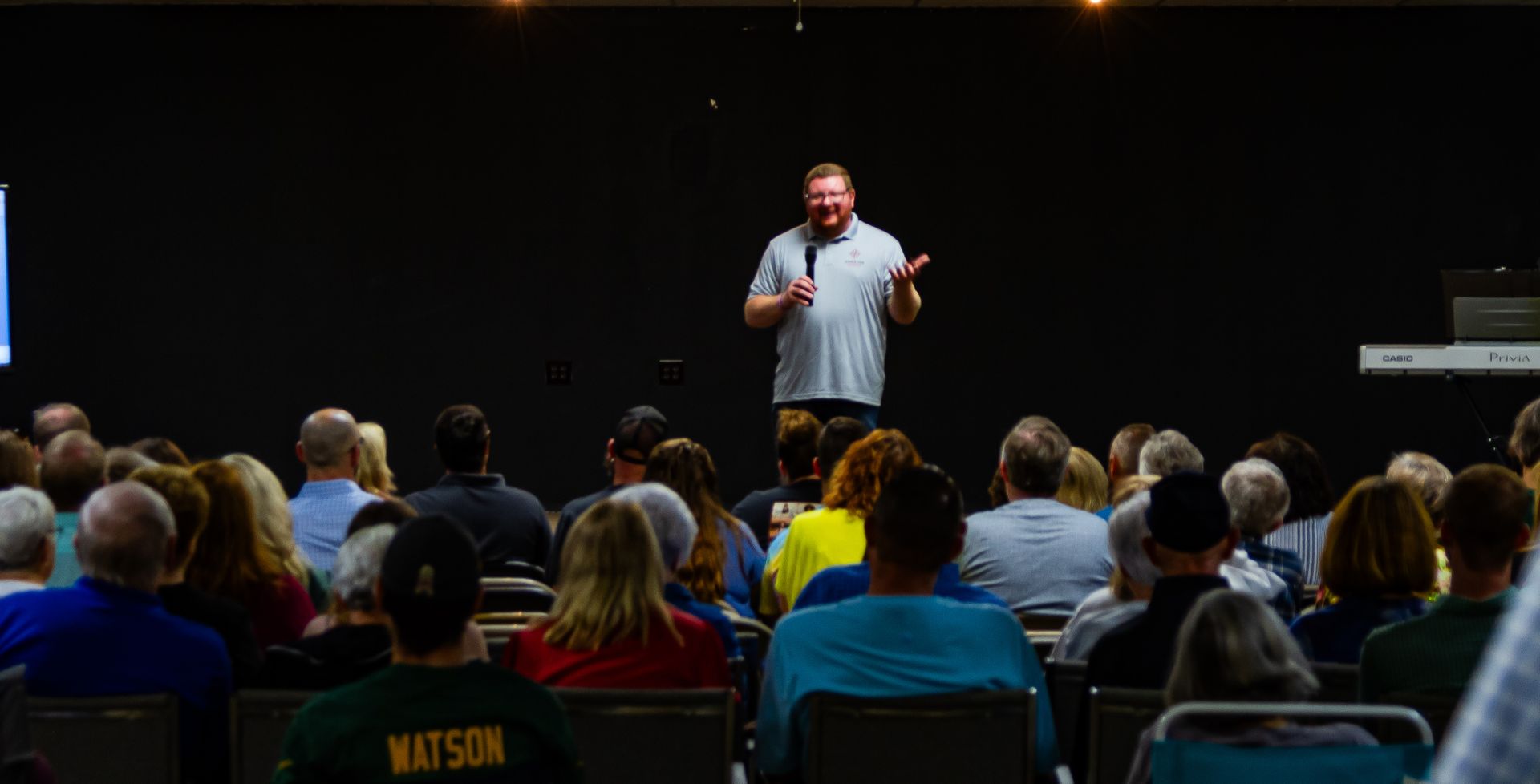 A man is giving a speech in front of a crowd of people in an auditorium.