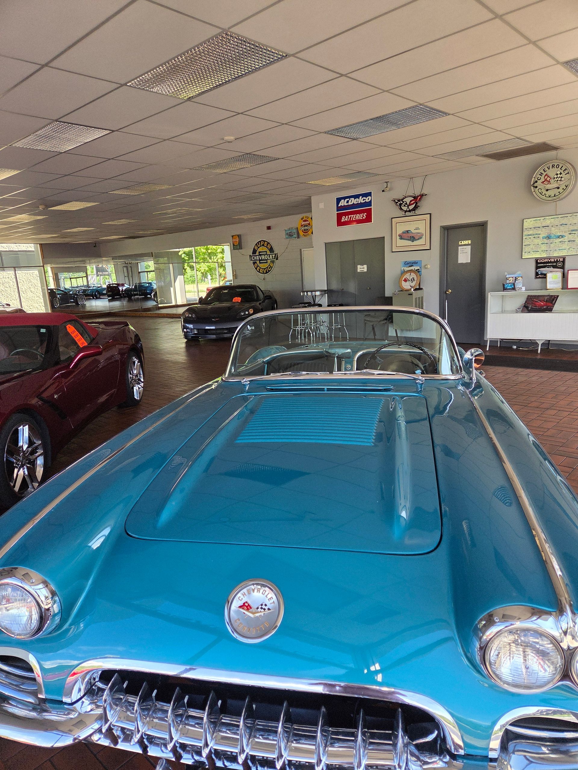 Blue vintage convertible car inside an indoor showroom, with other classic cars in the background