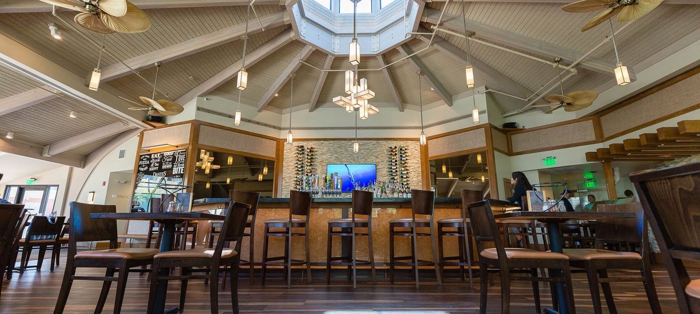 A restaurant with tables and chairs and a bar.