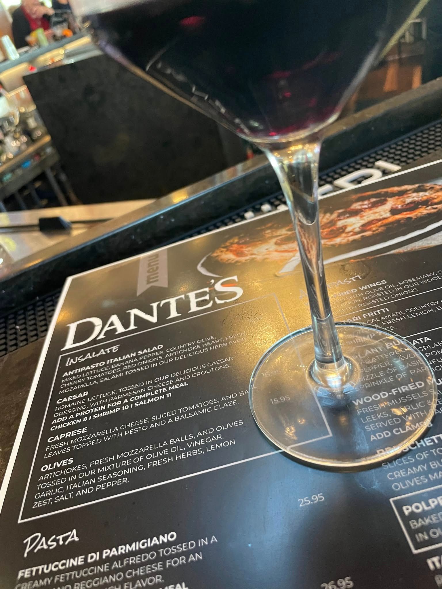 A martini glass sitting on top of a menu for dante 's