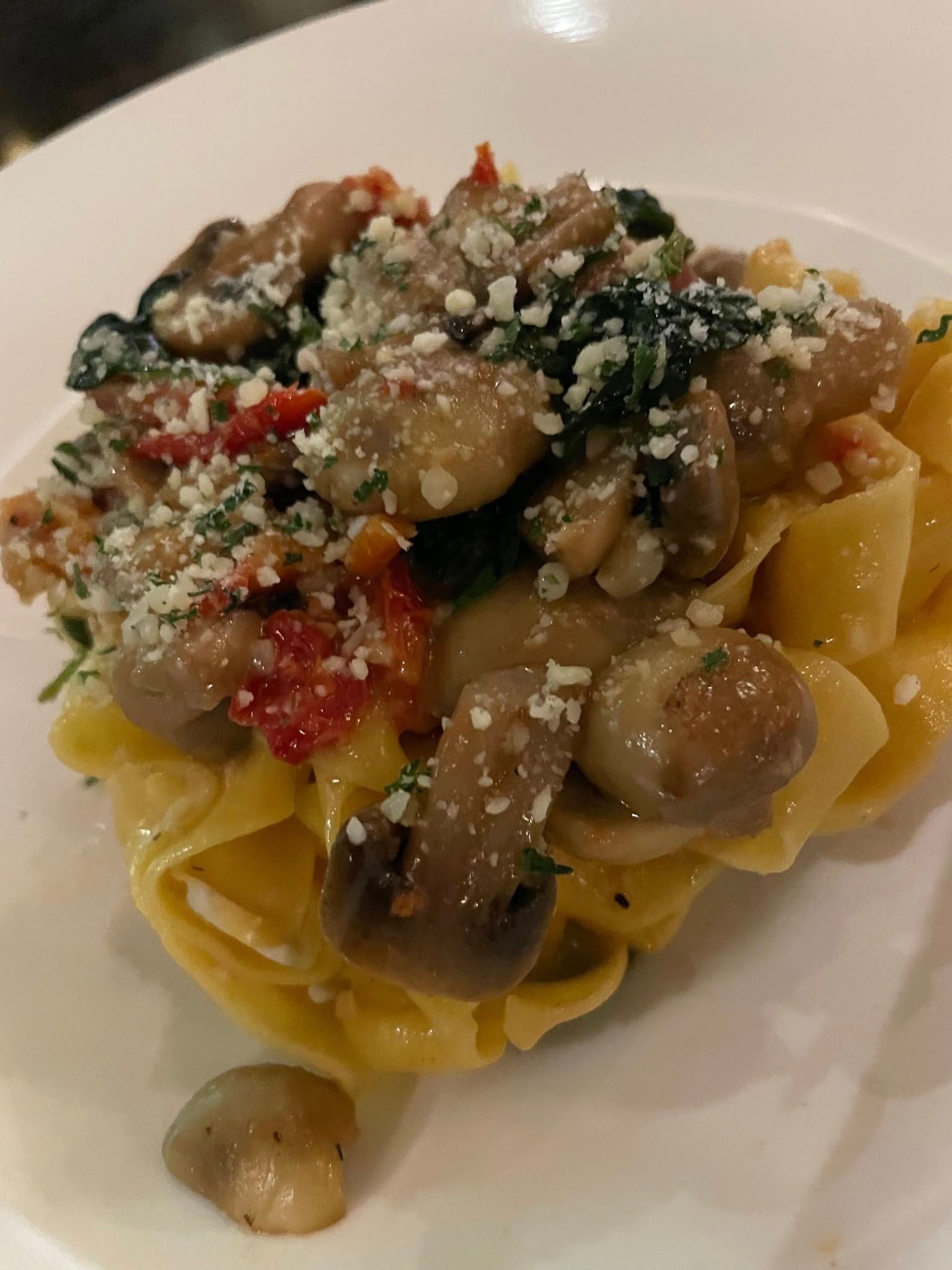 A close up of a plate of pasta with mushrooms and spinach