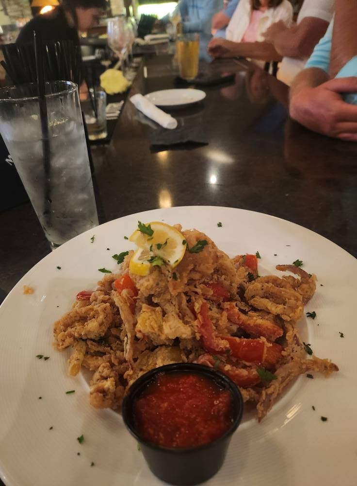 A plate of food with a small cup of sauce on it