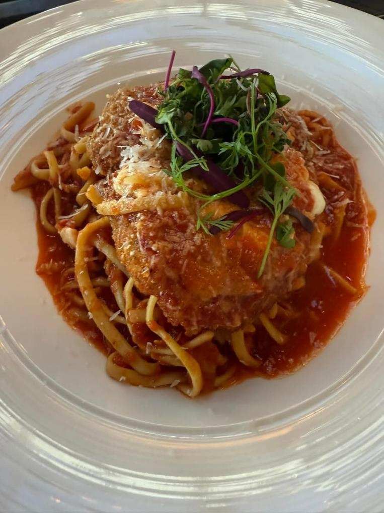 A close up of a plate of food with noodles and meat on a table.