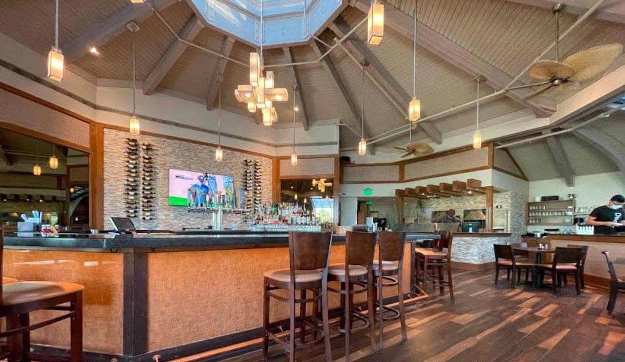 A restaurant with a bar , tables and chairs.