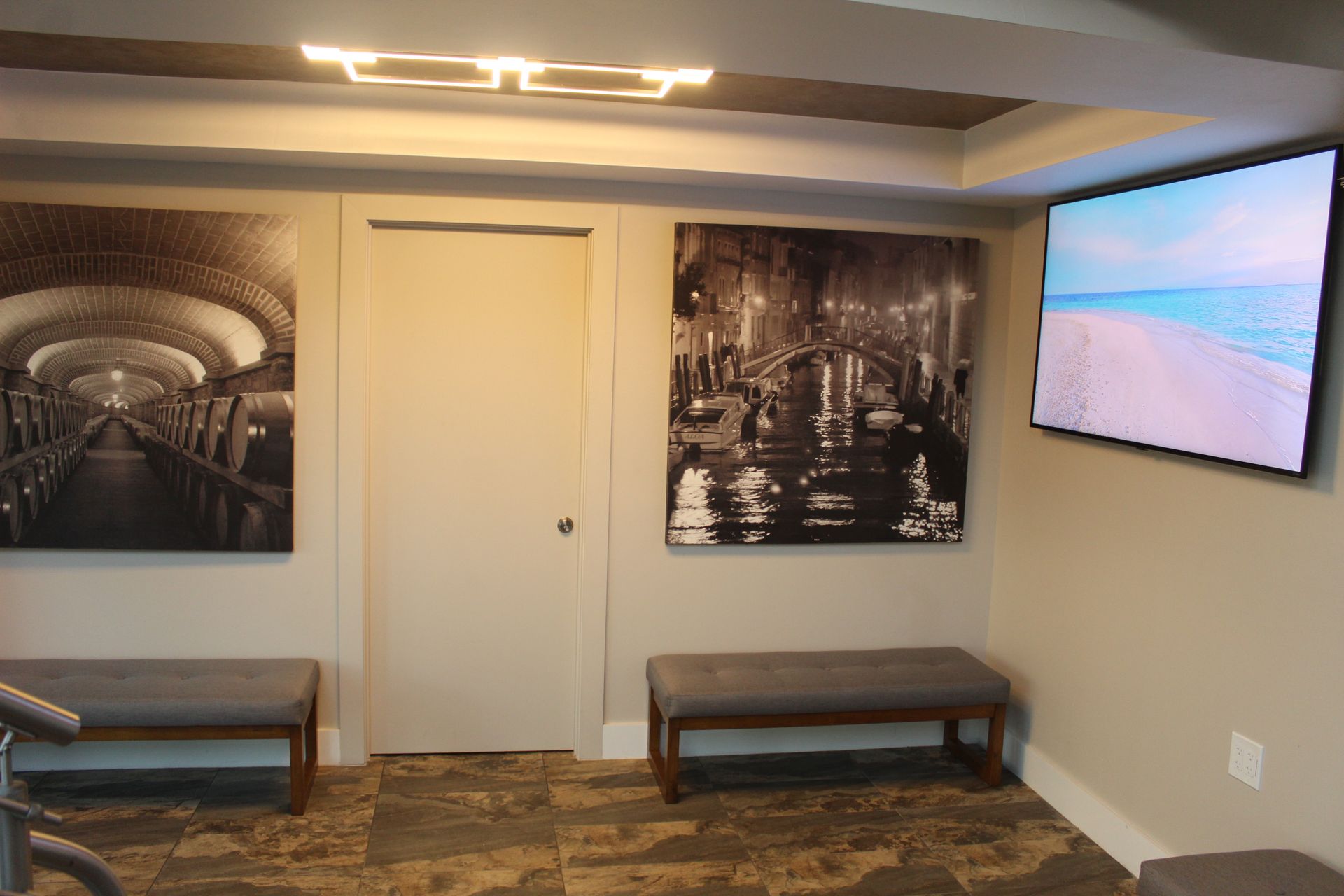 A room with two benches and a flat screen tv on the wall.