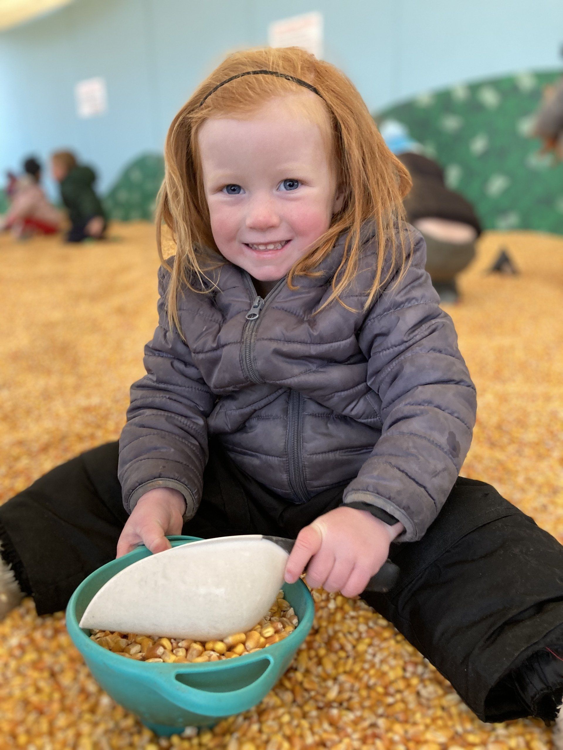 A little girl holding a bowl of corn