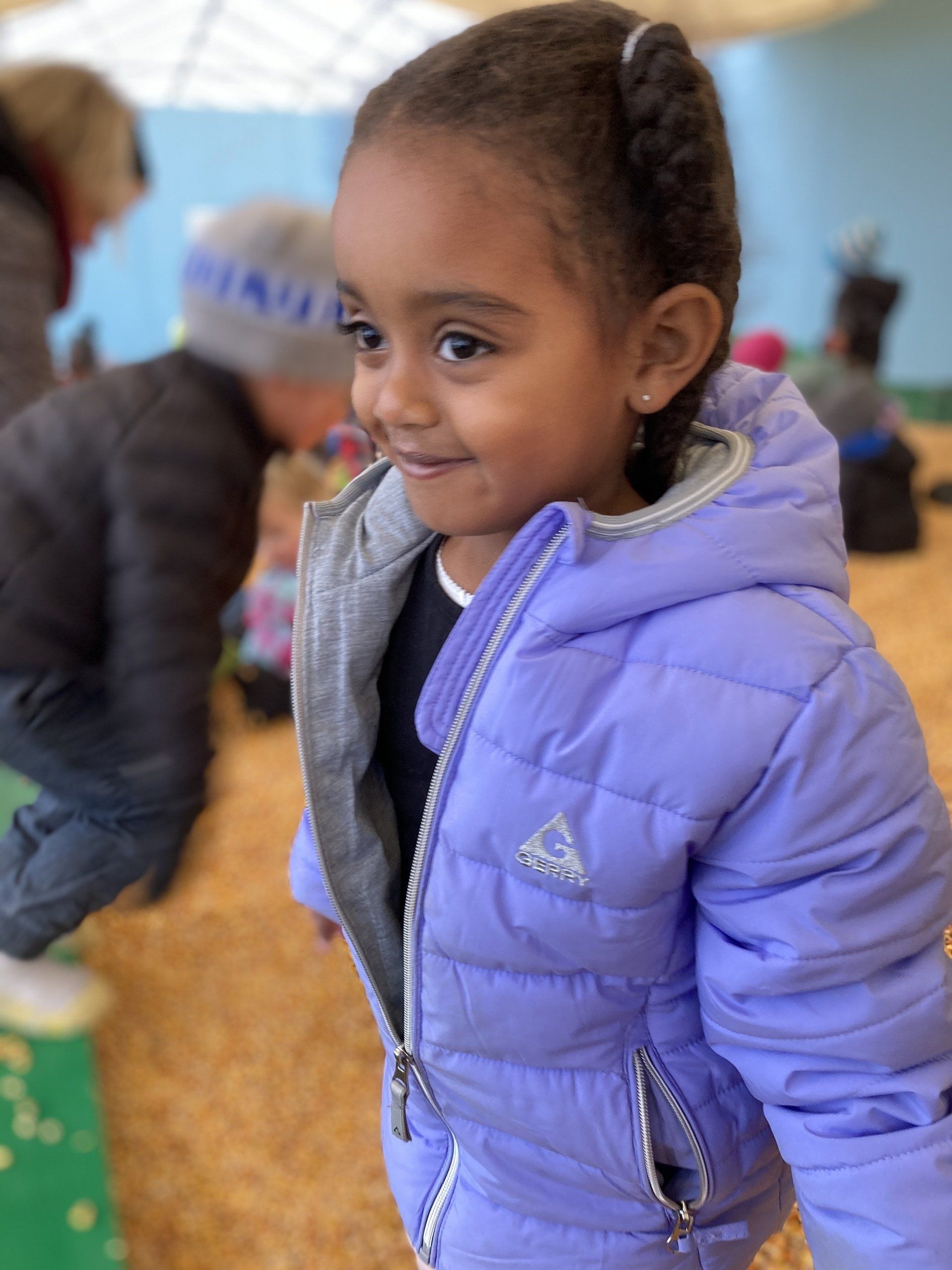 A little girl wearing a purple jacket 