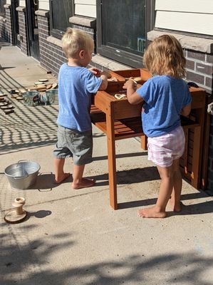 A boy and a girl are playing with a wooden table