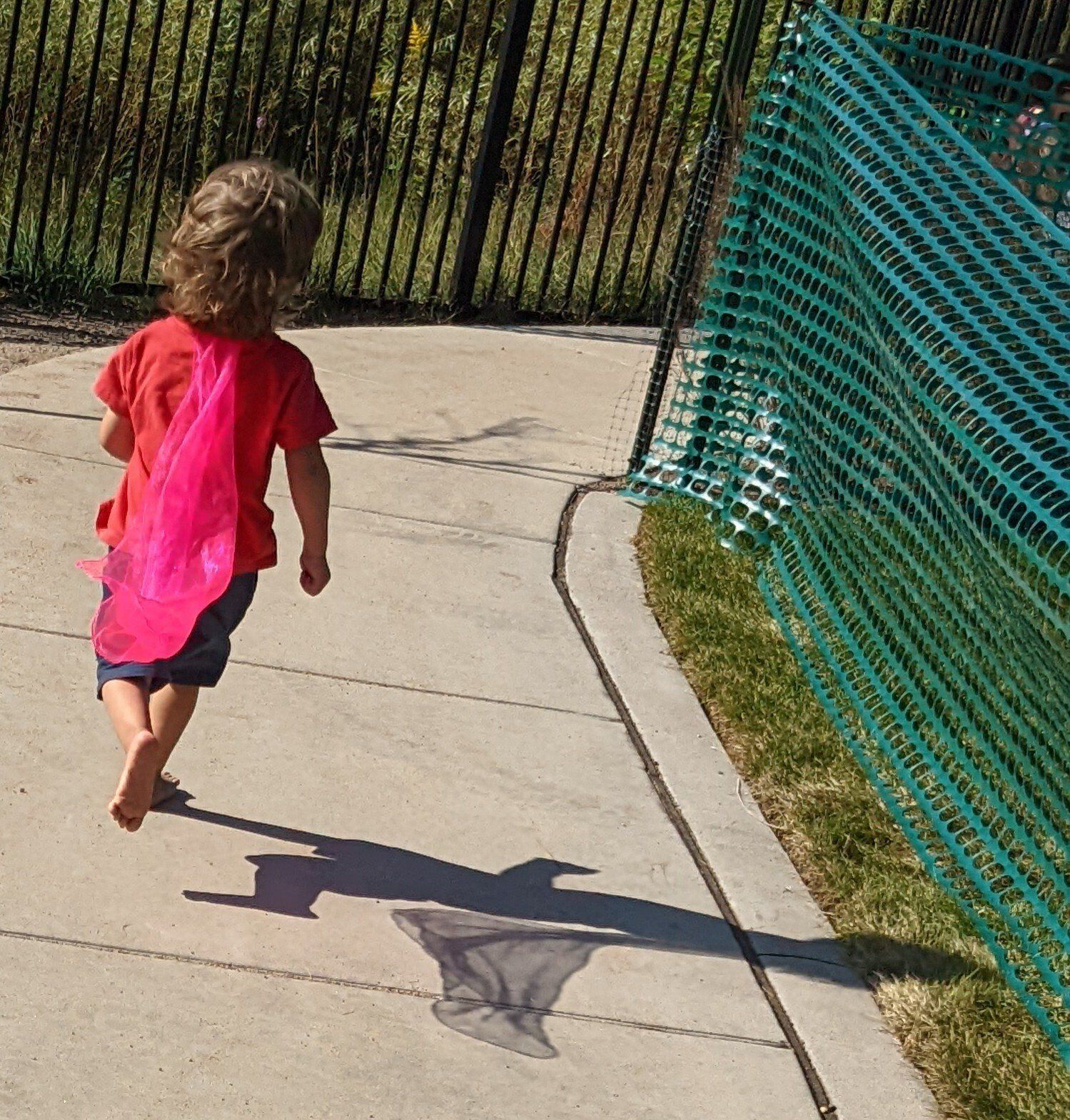 A little girl wearing a pink cape
