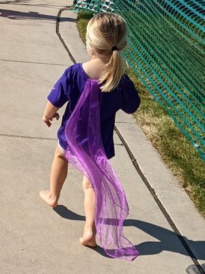 A little girl wearing a purple cape