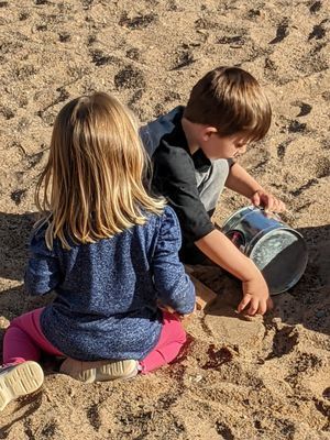 A boy and a girl are sitting in the sand 