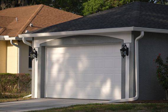White garage door on a suburban house with gray siding and a black lantern by the entry