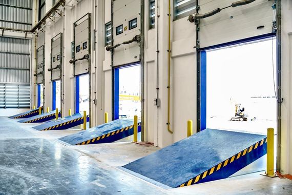 Loading dock with several blue ramps leading to open warehouse bay doors