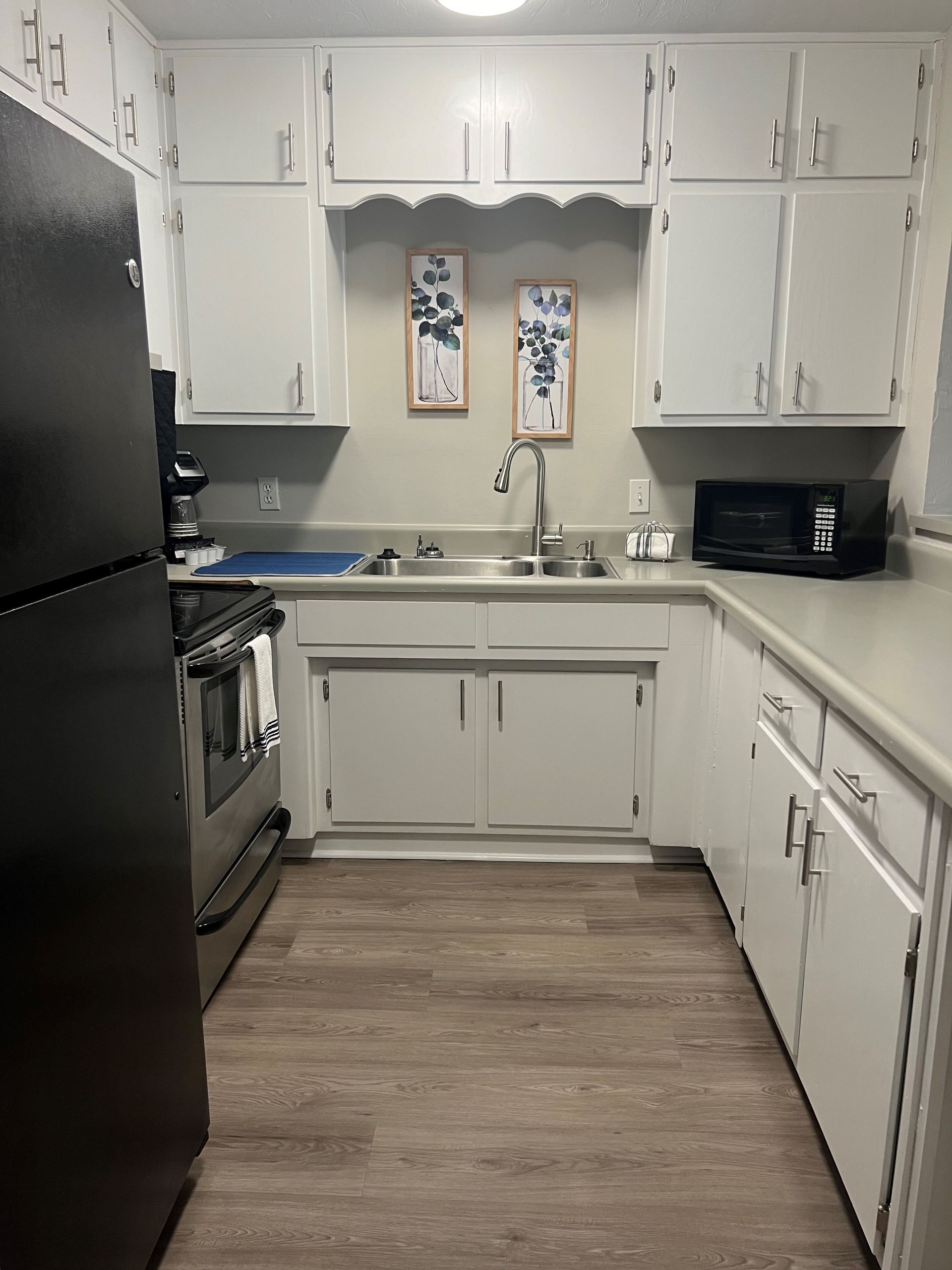 A kitchen with white cabinets and a black refrigerator