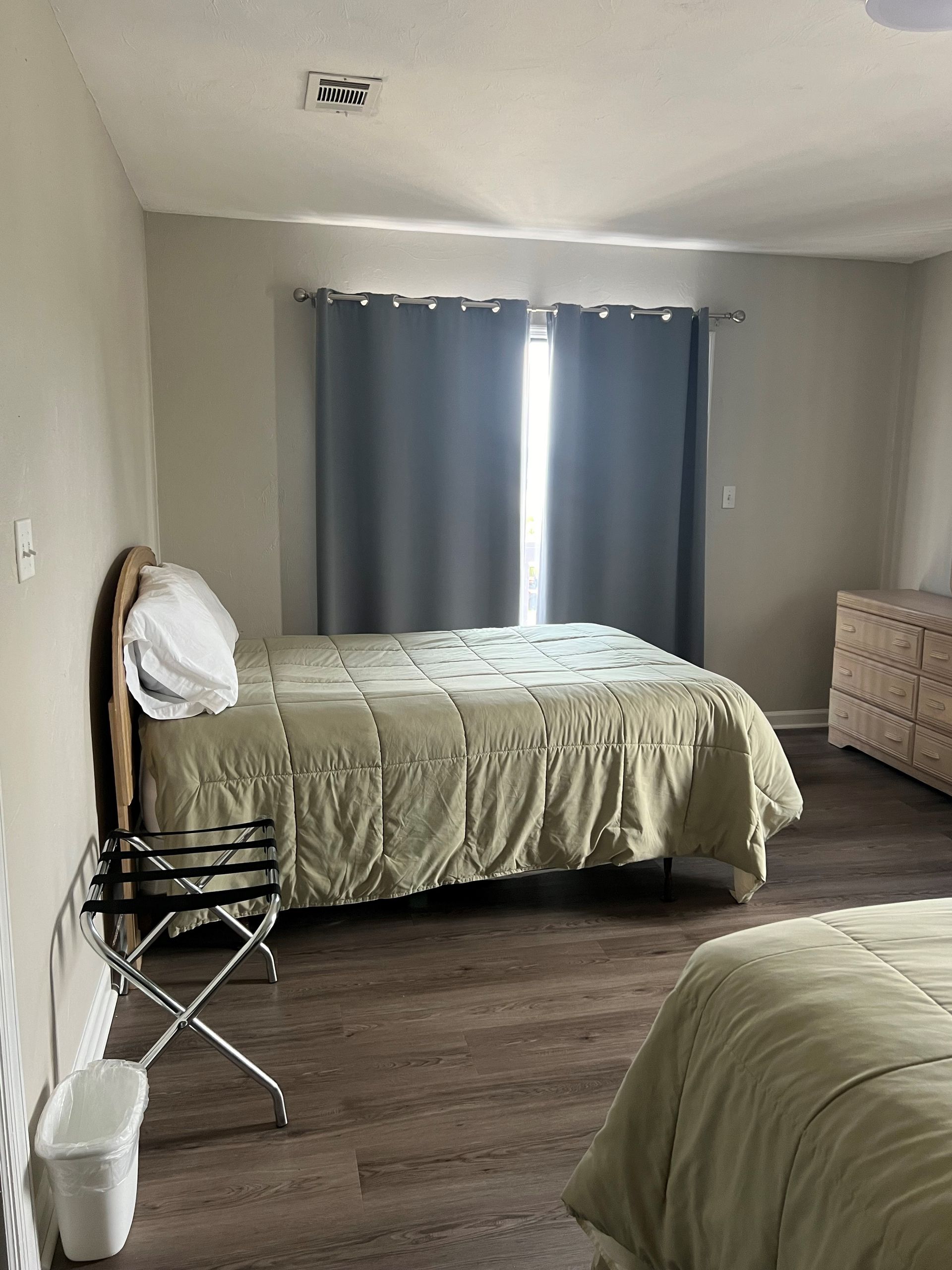 A bedroom with two beds , a dresser and a window.