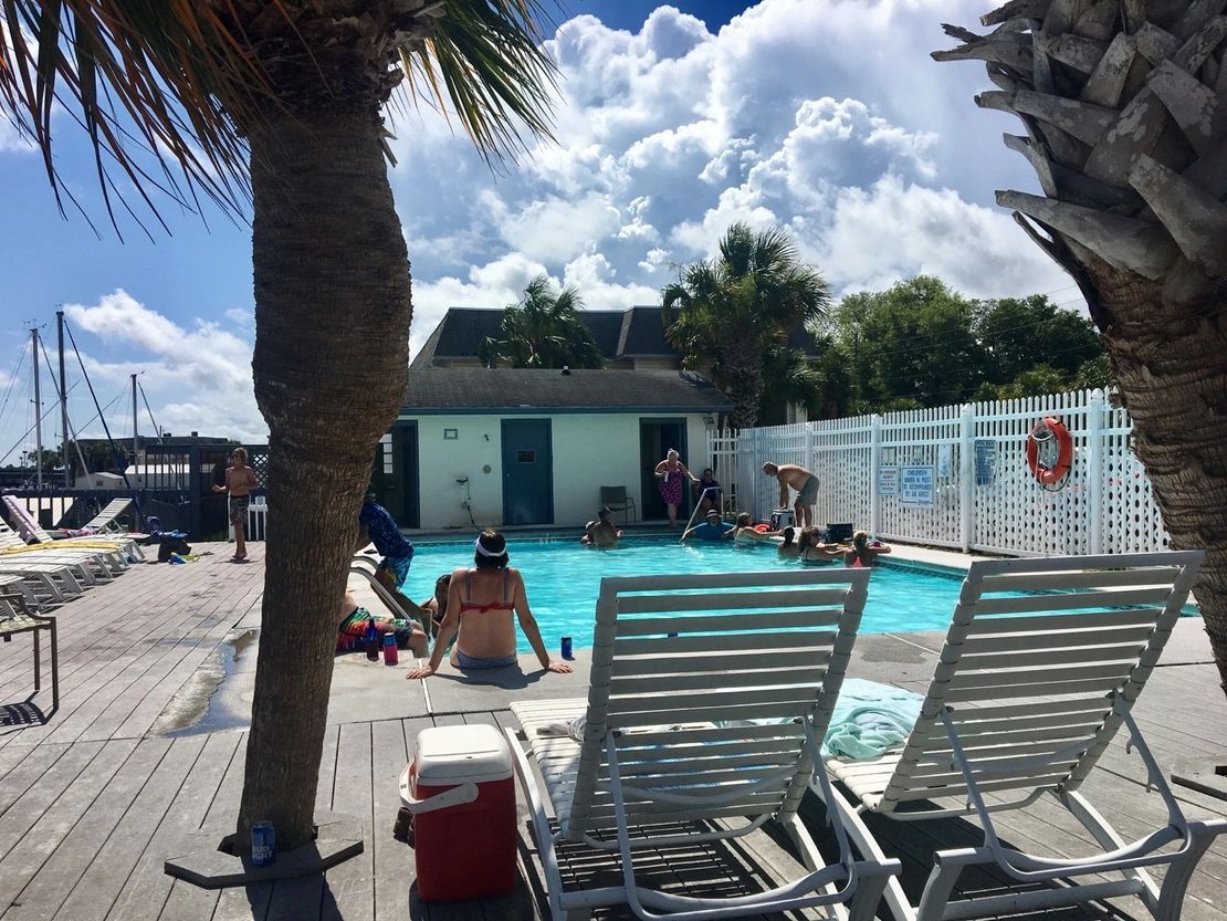 A woman is sitting in a chair near a swimming pool.