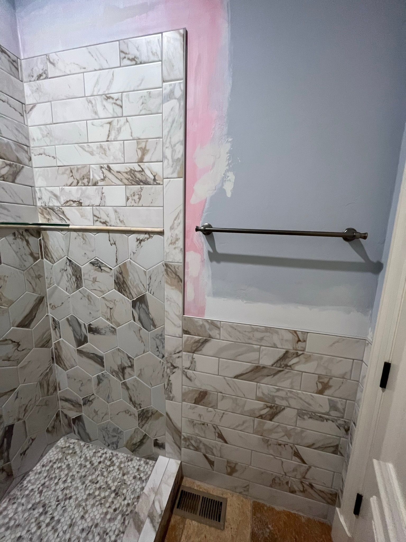 Bathroom remodel with tiled walls and a towel bar. A shower bench is visible.