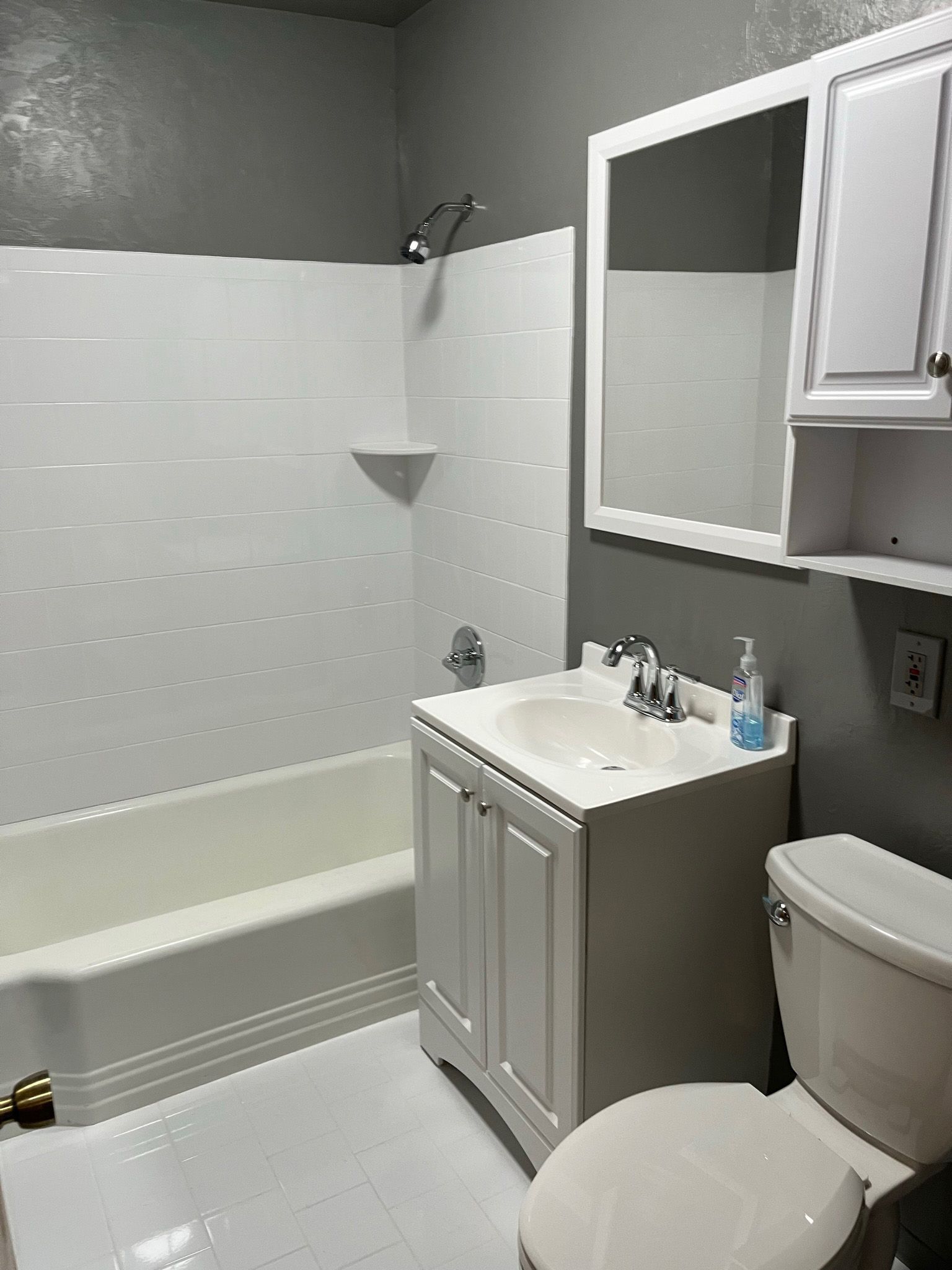 Small bathroom with white fixtures and gray walls.