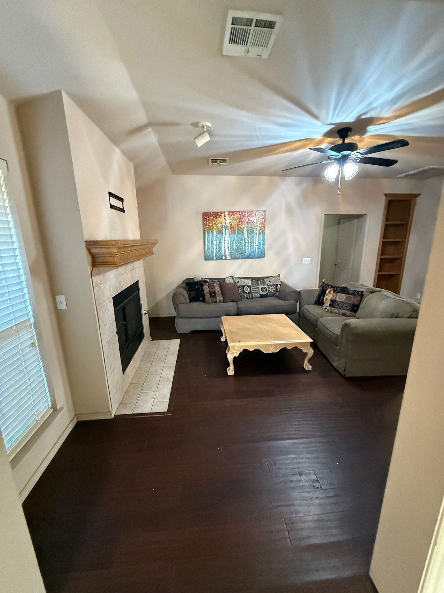 Living room with dark wood floors, two couches, a fireplace, and a coffee table.