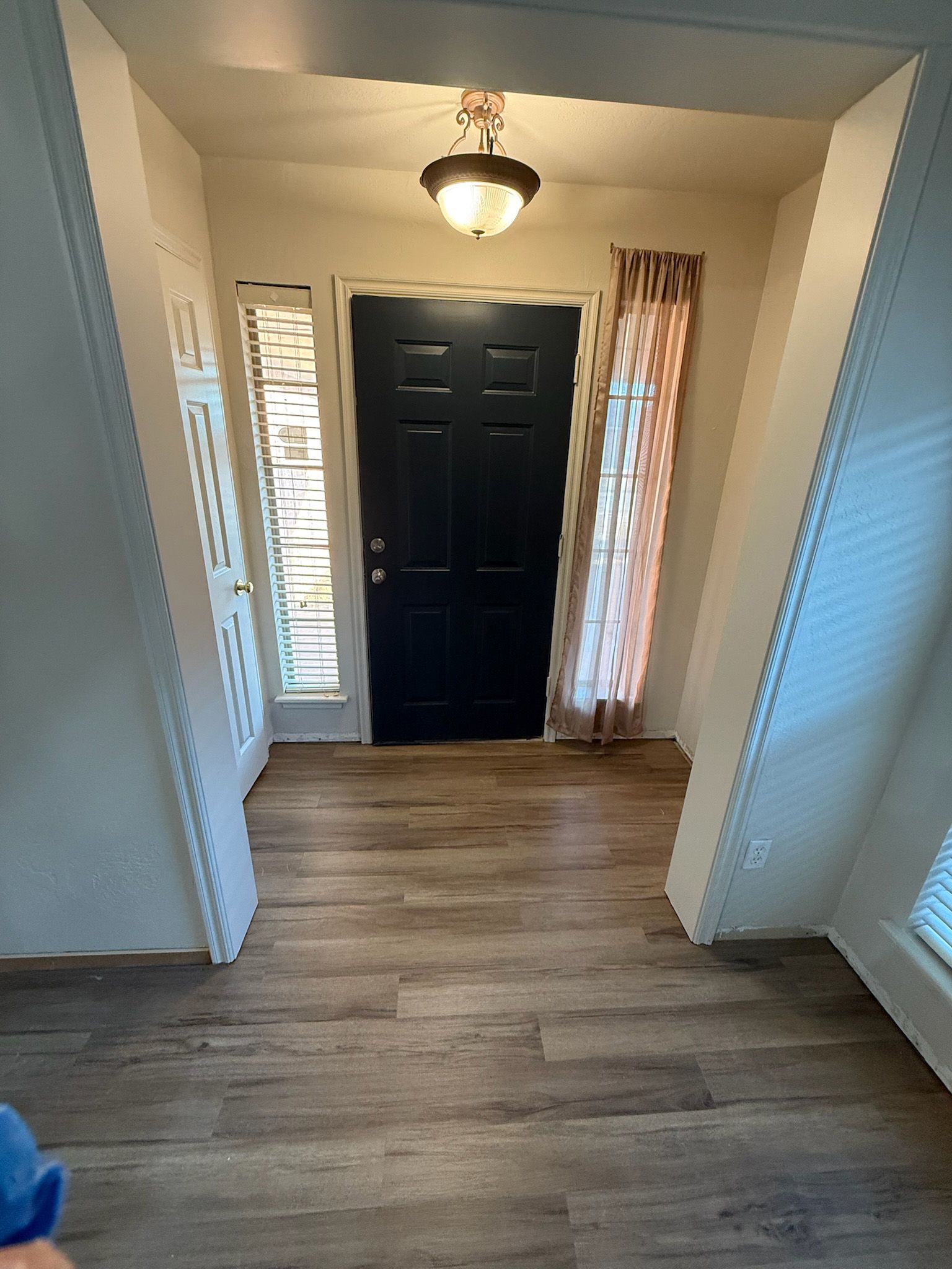 Entryway with a dark blue door, wood-look floor, and beige walls. A small window is on the left.