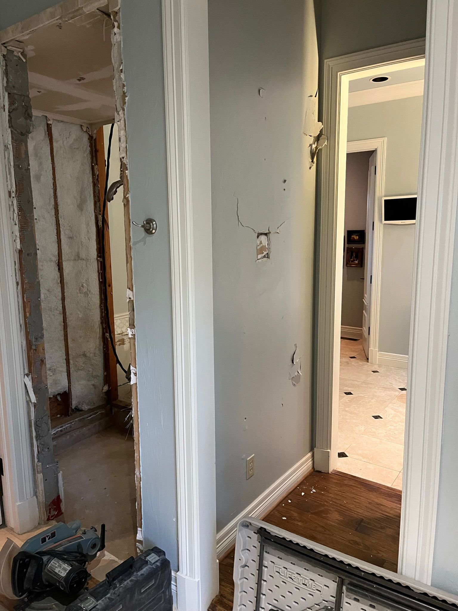 Hallway with doorways: one under construction, others lead to rooms with flooring.