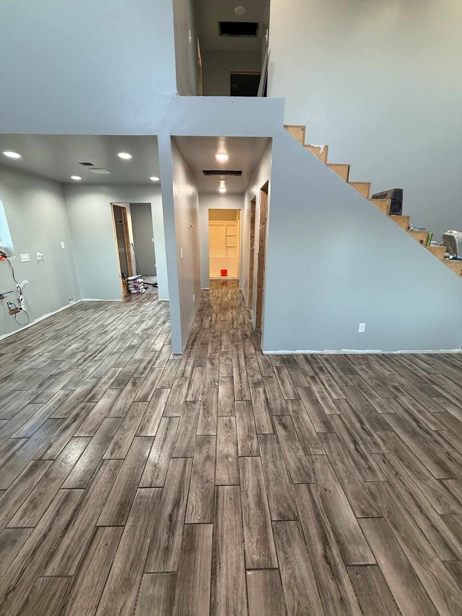 Newly constructed home interior with wood-look flooring, gray walls, and stairs leading up.