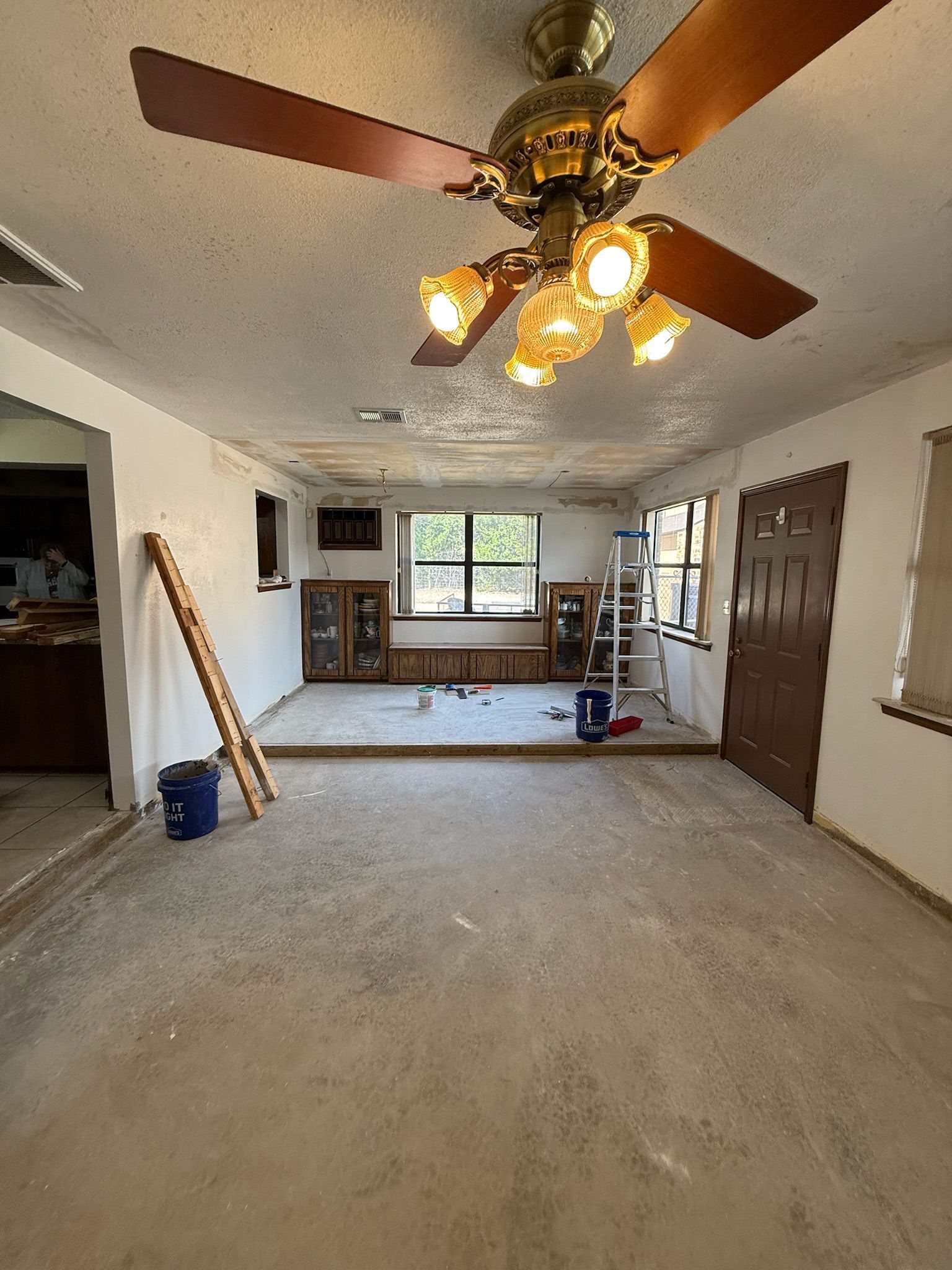 Renovated room with ceiling fan, exposed subfloor, and tools.