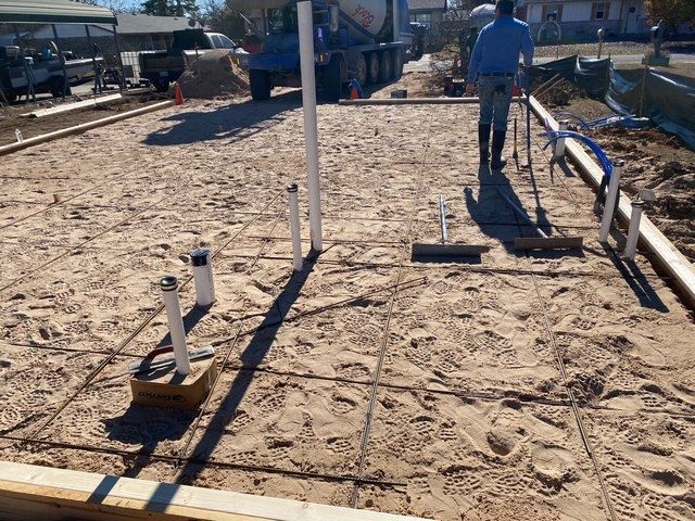 Construction site with plumbing, rebar, and a worker prepping for concrete pouring.