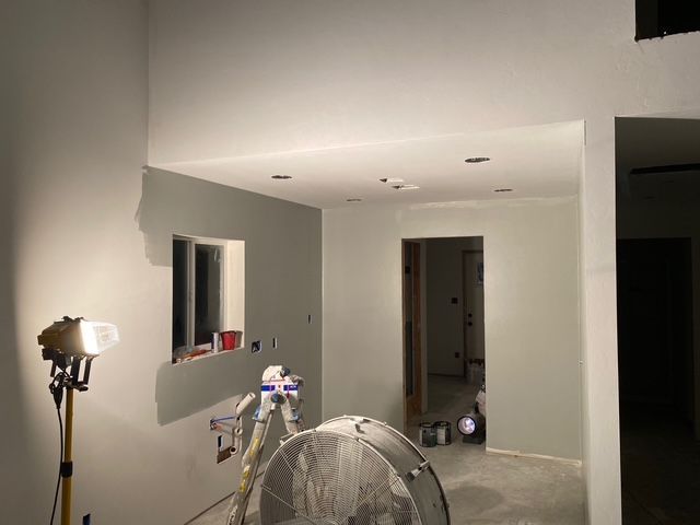 Room with freshly painted gray walls, spotlight, and large fan; construction site.