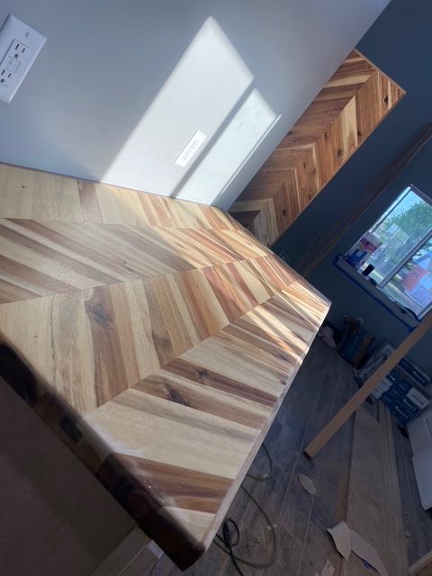 Wooden countertop with chevron pattern and herringbone backsplash.